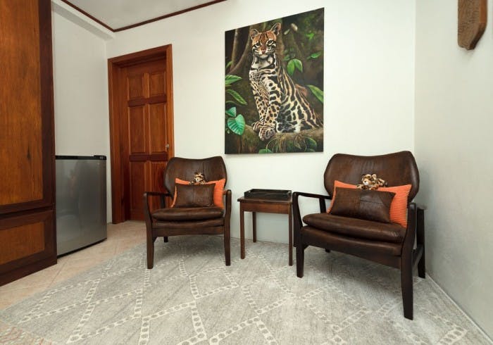 Two brown leather upholstered chairs with small table between and large picture of ocelot hanging above