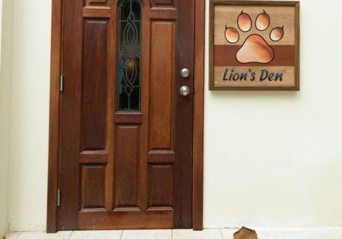 Exterior wooden door with decorative sign of lion's paw print with the words "Lion's Den"