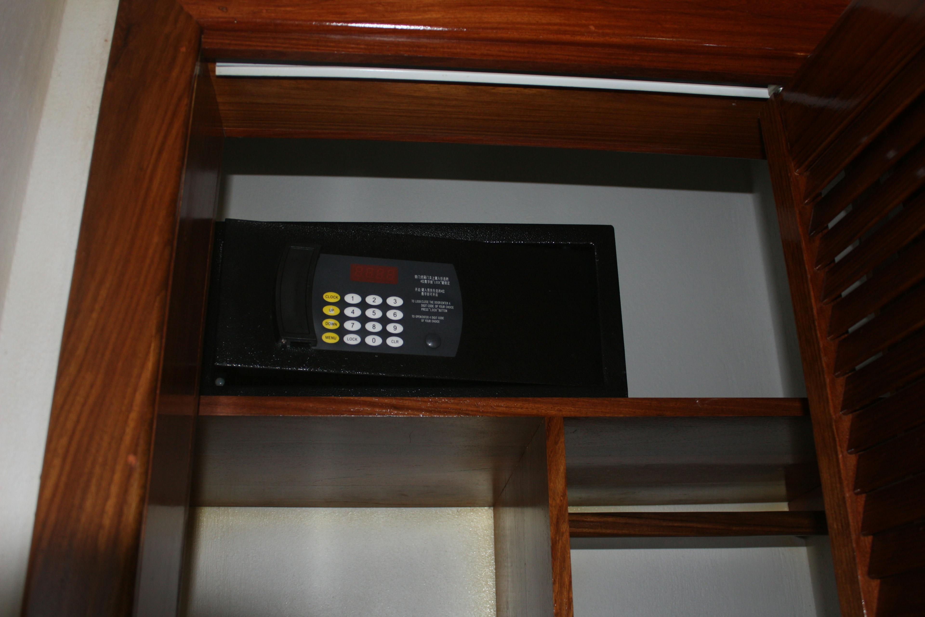 Wooden closet shelves with small black personal safe on one shelf