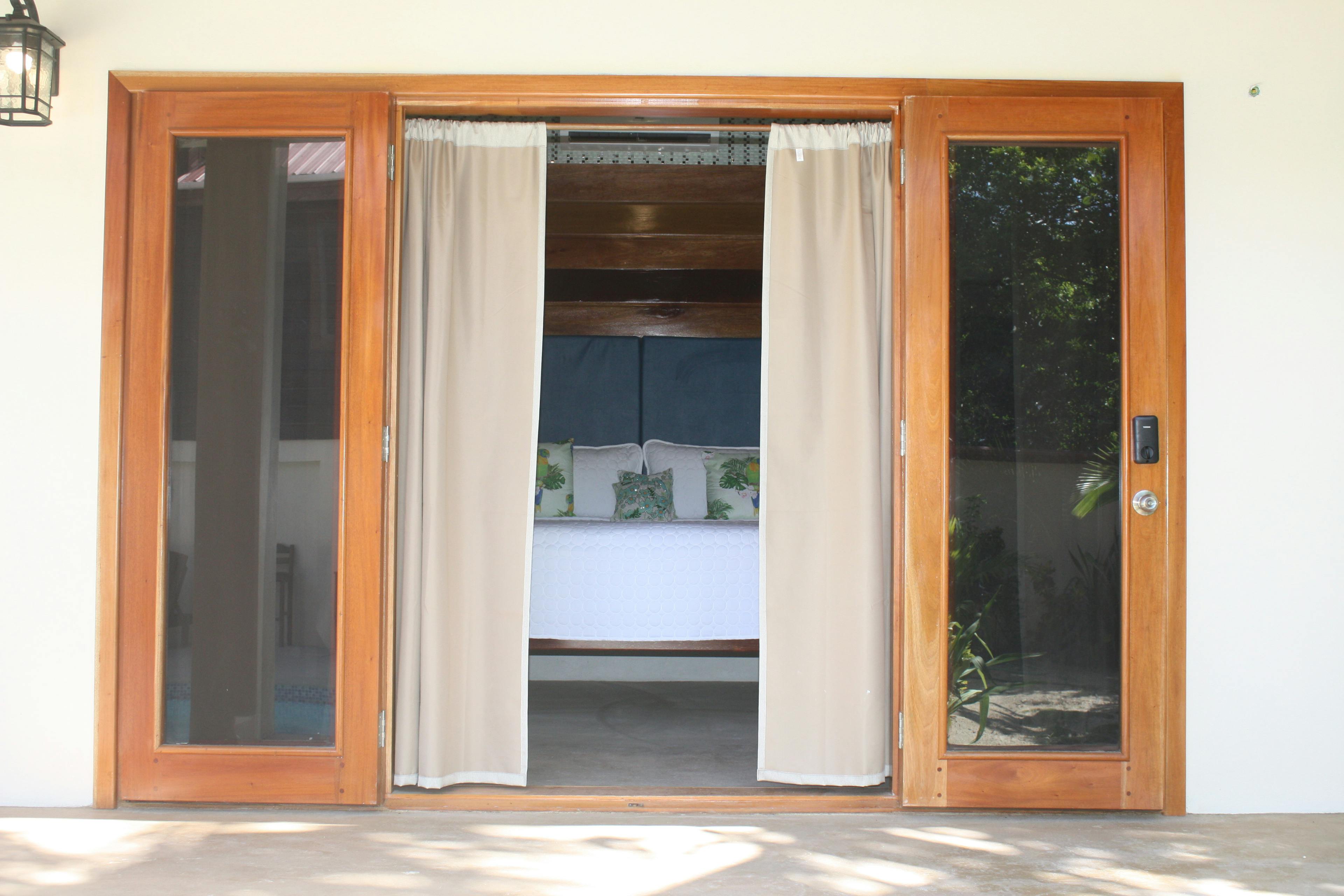 View from exterior pool deck through bedroom doors with drapes open